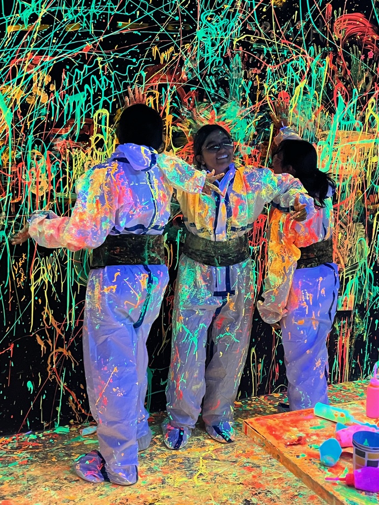 Colleagues covered in UV paint inside the neon splatter room